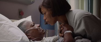 Movie still from “Whitney Houston: I Wanna Dance with Somebody” (2022), directed by Kasi Lemmons – A man and a woman in a hospital bed; Medium shot, Over the shoulder angle