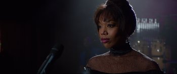 Movie still from “Whitney Houston: I Wanna Dance with Somebody” (2022), directed by Kasi Lemmons – A person holding a microphone; Close Up shot, Over the shoulder angle