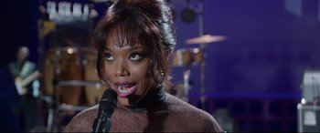 Movie still from “Whitney Houston: I Wanna Dance with Somebody” (2022), directed by Kasi Lemmons – A woman with her mouth wide open holding a microphone; Close Up shot, Over the shoulder angle