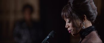 Movie still from “Whitney Houston: I Wanna Dance with Somebody” (2022), directed by Kasi Lemmons – A person holding a microphone; Close Up shot, Over the shoulder angle