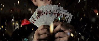 Movie still from “Who Am I” (2014), directed by Baran bo Odar – A person holding a deck of cards with a lit candle in front of them; Extreme Close Up shot, Overhead angle