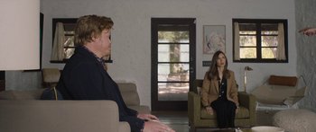 Movie still from “Windfall” (2022), directed by Charlie McDowell – A man and a woman sitting in a living room on couches; Wide shot, Over the shoulder angle