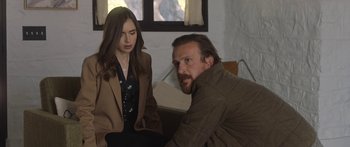 Movie still from “Windfall” (2022), directed by Charlie McDowell – A man and a woman sitting next to each other in front of a window; Medium shot, Over the shoulder angle