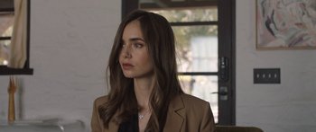 Movie still from “Windfall” (2022), directed by Charlie McDowell – A woman in a brown jacket looking to her left; Close Up shot, Over the shoulder angle