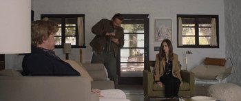 Movie still from “Windfall” (2022), directed by Charlie McDowell – A man and a woman sitting in a living room next to each other; Wide shot, Over the shoulder angle