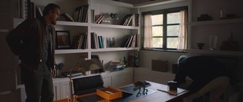 Movie still from “Windfall” (2022), directed by Charlie McDowell – A room with a lot of books on the shelves; Wide shot, High angle