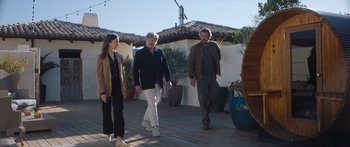 Movie still from “Windfall” (2022), directed by Charlie McDowell – A group of three people walking on a deck; Wide shot, Low angle