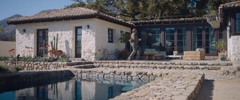 Movie still from “Windfall” (2022), directed by Charlie McDowell – A person walking near a pool near a house; Extreme Wide shot, High angle