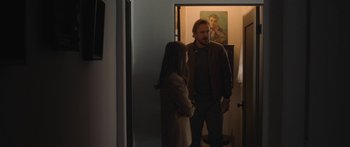 Movie still from “Windfall” (2022), directed by Charlie McDowell – A man and a woman standing in front of a painting; Medium shot, Over the shoulder angle