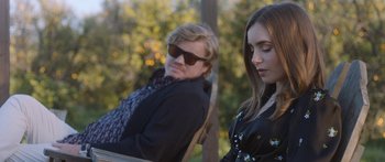 Movie still from “Windfall” (2022), directed by Charlie McDowell – A man and a woman sitting next to each other on a bench; Medium shot, Over the shoulder angle