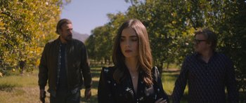 Movie still from “Windfall” (2022), directed by Charlie McDowell – A beautiful young lady standing in front of a tree; Medium shot, Over the shoulder angle