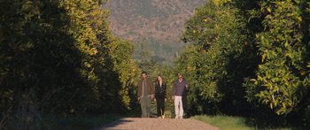 Movie still from “Windfall” (2022), directed by Charlie McDowell – A group of people standing next to each other on a dirt road; Wide shot, High angle