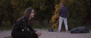 Movie still from “Windfall” (2022), directed by Charlie McDowell – A woman sitting on the side of a road next to a man; Wide shot, Over the shoulder angle