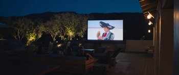 Movie still from “Windfall” (2022), directed by Charlie McDowell – People are sitting on a deck watching a movie; Wide shot, High angle