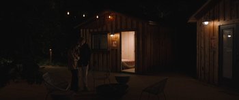 Movie still from “Windfall” (2022), directed by Charlie McDowell – Two people standing in front of a cabin at night; Wide shot, High angle