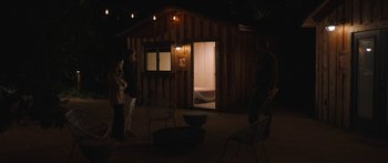 Movie still from “Windfall” (2022), directed by Charlie McDowell – A group of people standing in front of a cabin; Wide shot, Over the shoulder angle