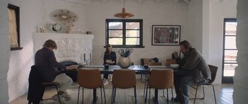 Movie still from “Windfall” (2022), directed by Charlie McDowell – A woman sitting at a dining room table; Wide shot, Over the shoulder angle