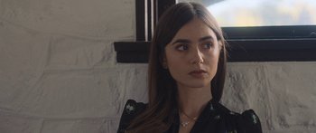 Movie still from “Windfall” (2022), directed by Charlie McDowell – A person with long hair wearing a necklace; Close Up shot, Over the shoulder angle