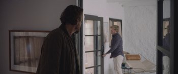Movie still from “Windfall” (2022), directed by Charlie McDowell – Two men standing in front of a window; Medium shot, Over the shoulder angle