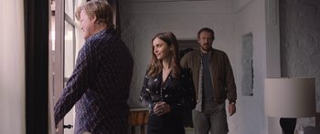 Movie still from “Windfall” (2022), directed by Charlie McDowell – A woman standing next to two men in a room; Medium shot, Over the shoulder angle