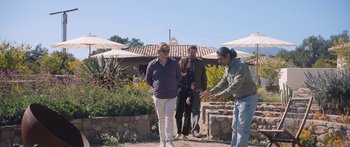 Movie still from “Windfall” (2022), directed by Charlie McDowell – Three people standing in front of a building; Wide shot, Over the shoulder angle
