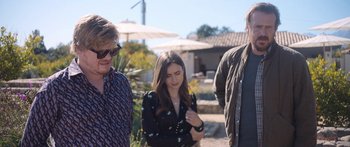 Movie still from “Windfall” (2022), directed by Charlie McDowell – A woman standing next to two other people outside; Medium shot, Over the shoulder angle