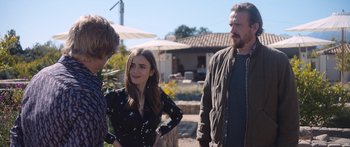 Movie still from “Windfall” (2022), directed by Charlie McDowell – A group of people standing next to each other on a field; Medium shot, Over the shoulder angle