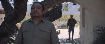 Movie still from “Windfall” (2022), directed by Charlie McDowell – A man standing next to another man under a tree; Medium shot, Over the shoulder angle