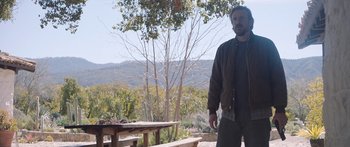 Movie still from “Windfall” (2022), directed by Charlie McDowell – A man standing next to a picnic table in a field; Medium shot, Over the shoulder angle