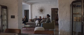 Movie still from “Windfall” (2022), directed by Charlie McDowell – Two women sitting on a couch in a living room; Wide shot, Over the shoulder angle