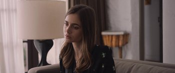 Movie still from “Windfall” (2022), directed by Charlie McDowell – A woman sitting on top of a couch in front of a window; Close Up shot, Over the shoulder angle