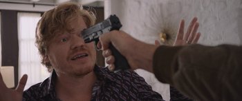 Movie still from “Windfall” (2022), directed by Charlie McDowell – A man holding a gun up to his face; Close Up shot, Over the shoulder angle