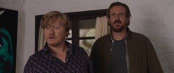 Movie still from “Windfall” (2022), directed by Charlie McDowell – Two men standing next to each other in front of a window; Close Up shot, Low angle