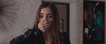 Movie still from “Windfall” (2022), directed by Charlie McDowell – A woman covers her mouth with her hands; Close Up shot, Over the shoulder angle