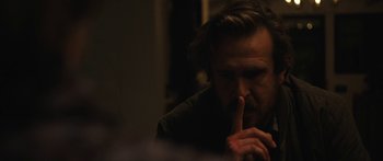 Movie still from “Windfall” (2022), directed by Charlie McDowell – A man sitting in front of a mirror with his finger on his lips; Close Up shot, Over the shoulder angle
