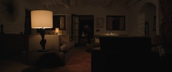 Movie still from “Windfall” (2022), directed by Charlie McDowell – A man standing in a living room in front of a door; Extreme Wide shot, High angle