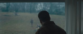 Movie still from “Wormwood” (2017), directed by Errol Morris – A man looking out of a window at people in a field; Medium shot, Over the shoulder angle