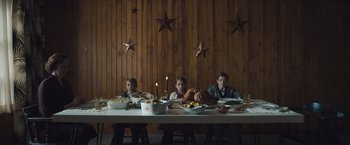 Movie still from “Wormwood” (2017), directed by Errol Morris – A group of people sitting at a table with food on it; Wide shot, Low angle