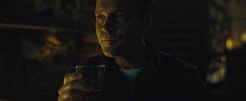 Movie still from “Wormwood” (2017), directed by Errol Morris – A man holding a glass of water in a dimly - lit room; Close Up shot, Over the shoulder angle