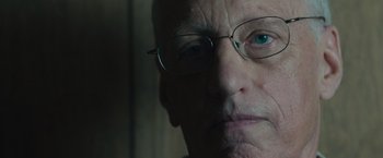 Movie still from “Wormwood” (2017), directed by Errol Morris – An older man wearing glasses looking at the camera; Close Up shot, Low angle