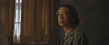 Movie still from “Wormwood” (2017), directed by Errol Morris – A woman with short brown hair is looking to her left; Close Up shot, Low angle