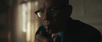Movie still from “Wormwood” (2017), directed by Errol Morris – An older man wearing glasses is smoking a pipe; Close Up shot, Over the shoulder angle