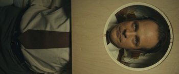 Movie still from “Wormwood” (2017), directed by Errol Morris – A man's face is reflected in a mirror; Close Up shot, Overhead angle