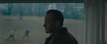 Movie still from “Wormwood” (2017), directed by Errol Morris – A man in a brown jacket is looking out a window; Close Up shot, Low angle