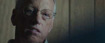 Movie still from “Wormwood” (2017), directed by Errol Morris – An older man wearing glasses looking at the camera; Close Up shot, Low angle