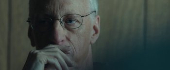 Movie still from “Wormwood” (2017), directed by Errol Morris – An older man wearing glasses and holding his hands to his face; Close Up shot, Over the shoulder angle