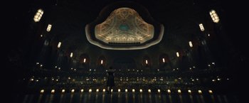A person standing in a room lit by candles
