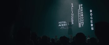 Movie still from “Wormwood” (2017), directed by Errol Morris – A woman standing in front of an audience on a stage; Wide shot, Low angle