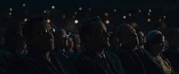 Movie still from “Wormwood” (2017), directed by Errol Morris – A group of people sitting in a dark room at night; Medium shot, Over the shoulder angle