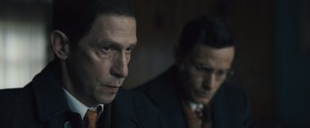 Movie still from “Wormwood” (2017), directed by Errol Morris – A man in a suit and tie next to another man in a suit and tie; Close Up shot, Over the shoulder angle